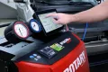 Rotary A/C recovery machines with digital interface and pressure gauges in an automotive repair shop.