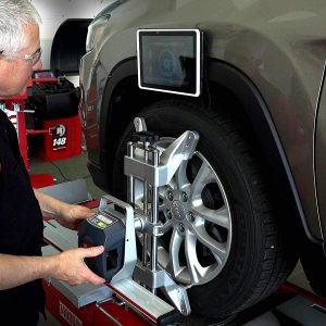 Technician using the R1065 wheel alignment machine on a vehicle
