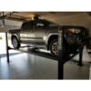 Gray pickup truck on a Direct Lift four-post lift inside a garage, highlighting the lift's use for elevating large vehicles in a home garage setting.