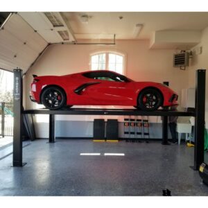 Red sports car elevated on a Direct Lift four-post lift in a clean, organized garage, emphasizing the lift's design and utility for car storage and maintenance.