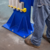 Baseplate of the Forward Lift DP15 two-post vehicle lift with aircraft-grade aluminum truck adapter extensions stored on the column bracket; worker standing nearby for scale.