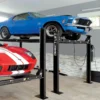 Direct Lift four-post automotive lift holding a blue classic Mustang and a red sports car in a modern garage with tiled walls and bright lighting.