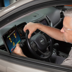 Technician operating the Rotary R1085 Pro 3D Wheel Aligner tablet from inside a vehicle, displaying intuitive controls for quick and accurate wheel alignment.