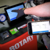 Technician operating the Rotary R3AC80 A/C cart remotely using a mobile phone app for diagnostics.