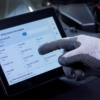 Technician operating the Rotary R3AC80 A/C cart touchscreen interface while wearing gloves.