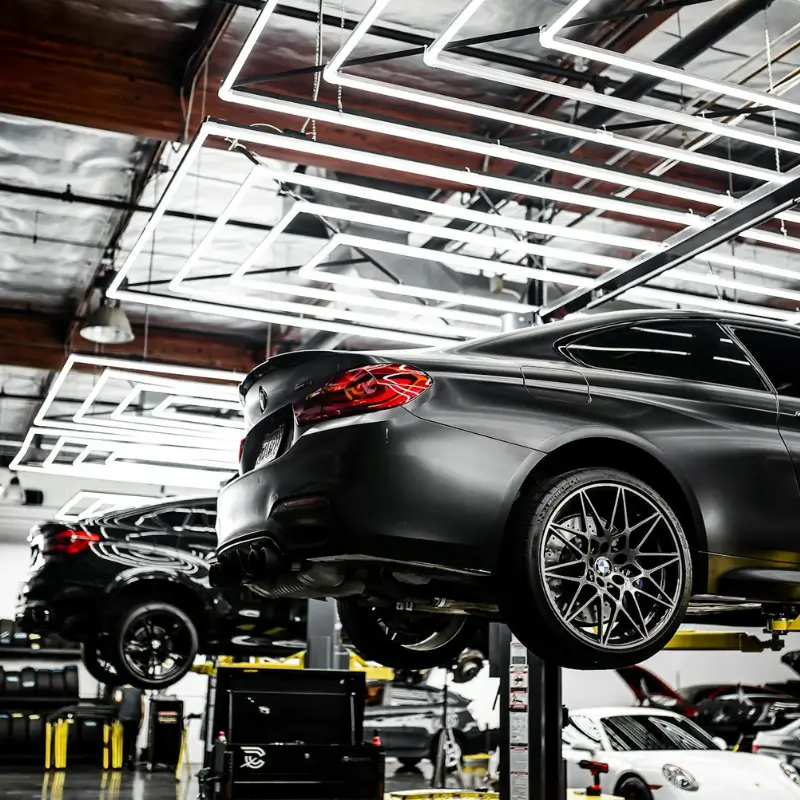 BMW on alignment lift in high-end automotive service shop with modern LED lighting