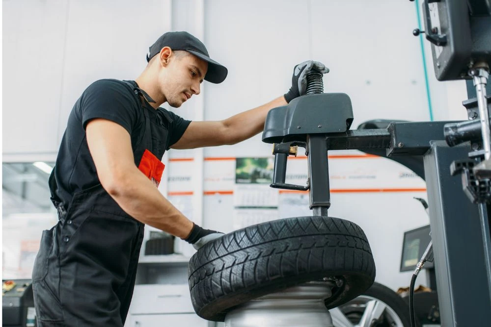 Technician using a tire changer machine to mount a tire in an auto shop, illustrating year-end automotive equipment upgrades.