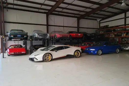 Lamborghini Huracán and classic sports cars stored on 4-post lifts in a large private collection space