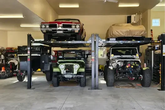 Classic and off-road vehicles stacked on multiple 4-post lifts in a residential garage