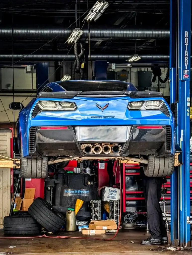 blue corvette on a two post Rotary lift inside a garage